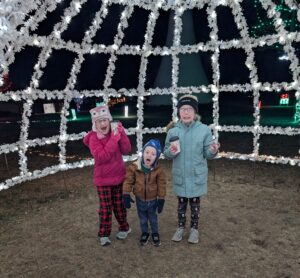 three children enjoying Christmas lights